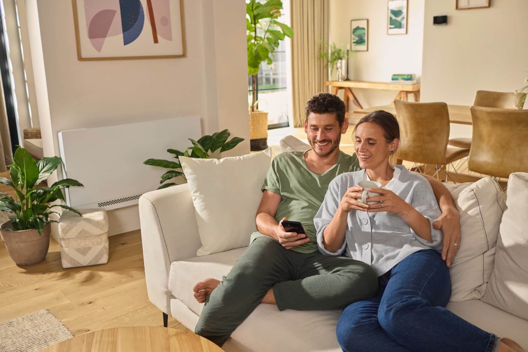 Porelė, sėdinti ant sofos ir žiūrinti į išmanųjį telefoną