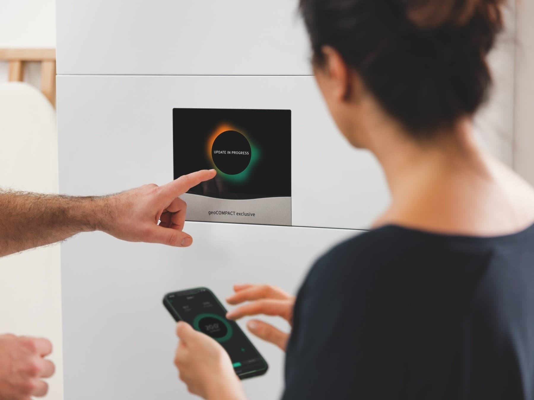 Vyras įveda duomenis į geoCOMPACT ekraną. Moteris žiūri į duomenis savo išmaniajame telefone